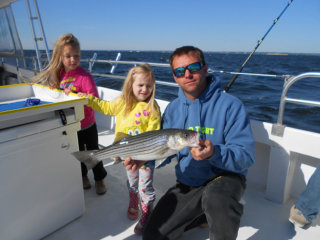 man holding fish with two little girls